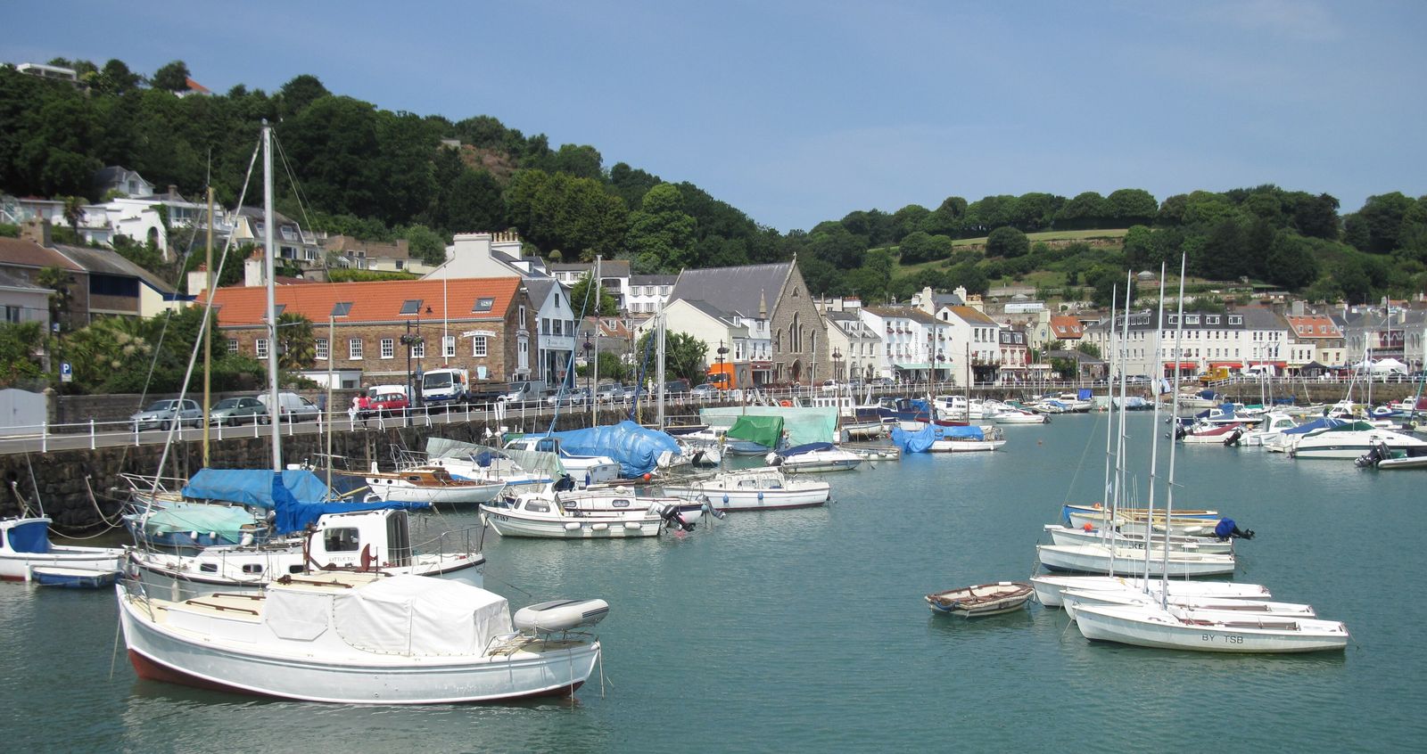 Boats moored in St Aubin harbour, Jersey, Channel Islands, with the village behind.