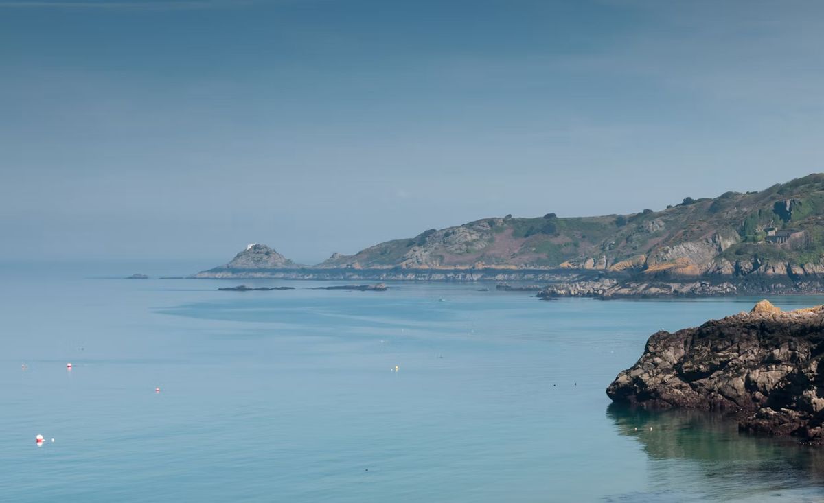 Calm sea and granite cliffs at Bouley Bay, Trinity, on the north coast of Jersey, Channel Islands.