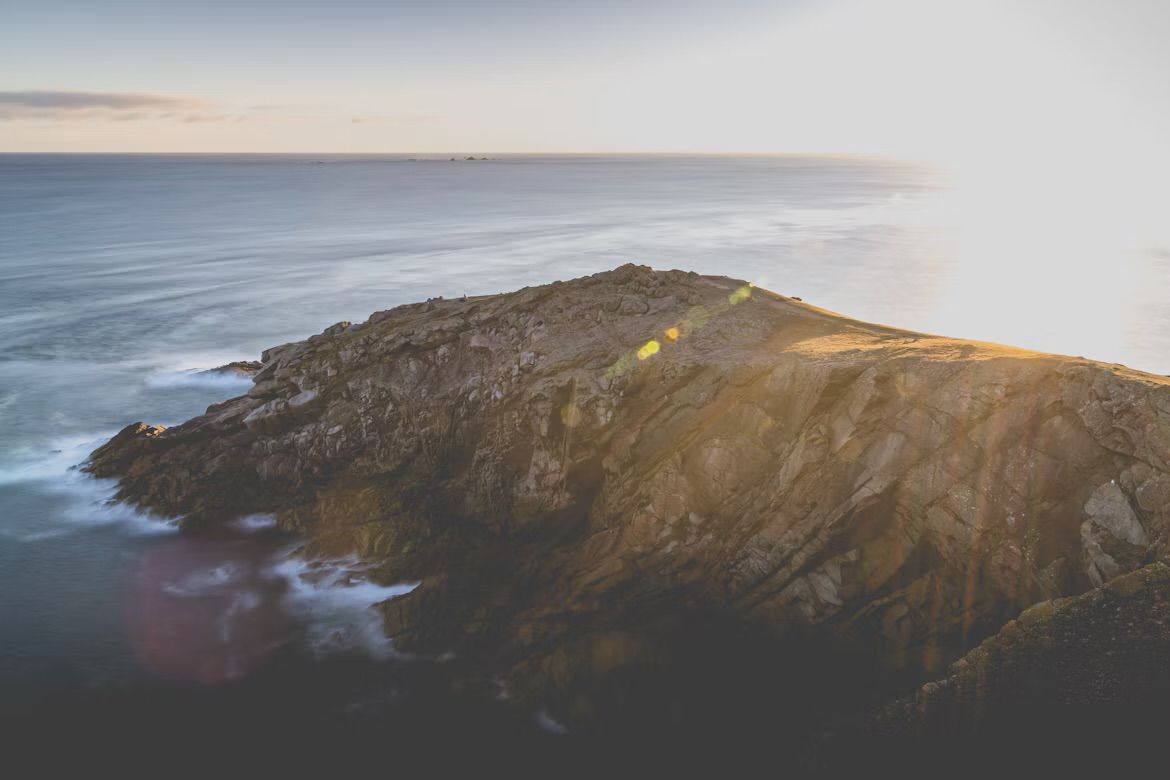 The rocky Petite Plémont headland on the north coast of Jersey, Channel Islands, in low sun, with the sea beyond.